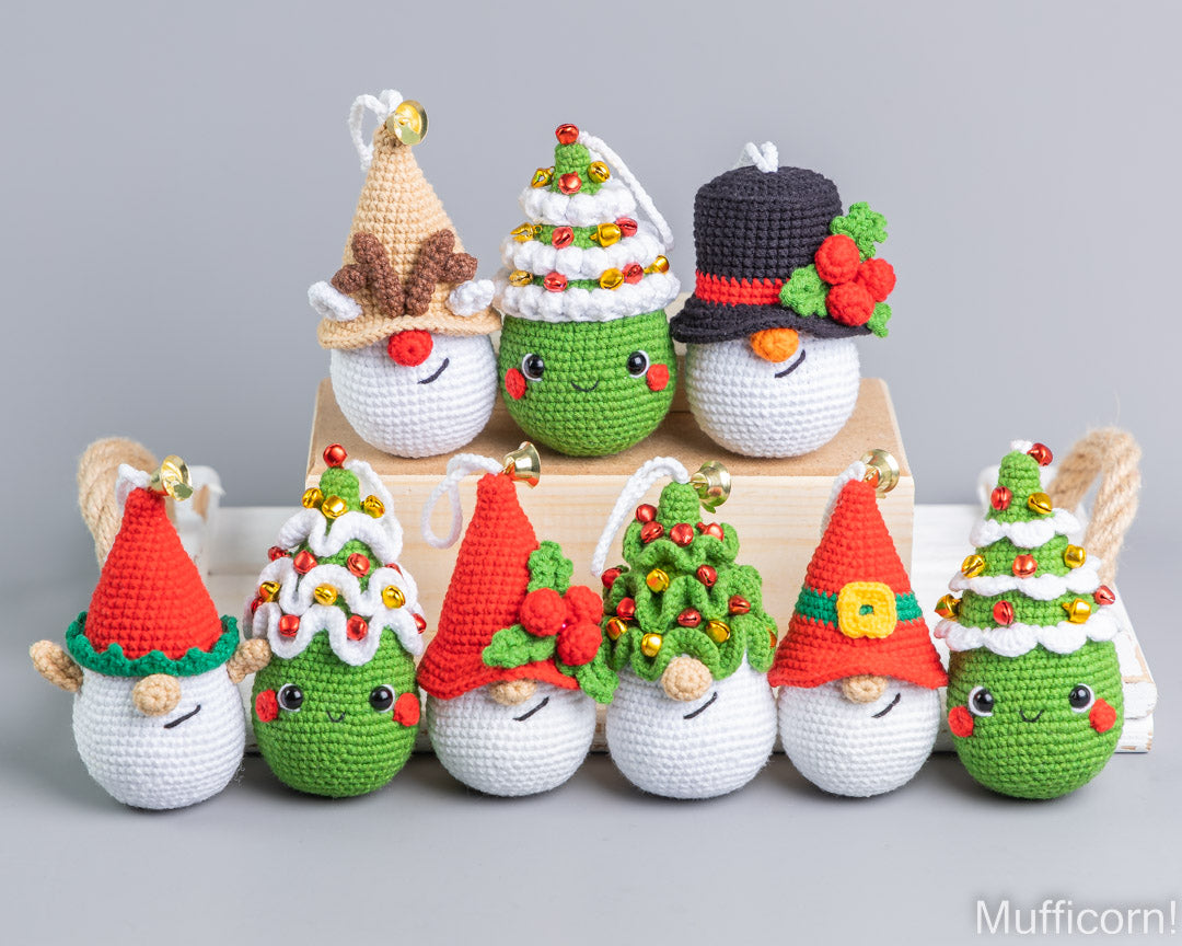 A set of eight handmade crocheted Christmas ornament gnomes in various holiday outfits, arranged on and around a light wooden block against a solid gray background.