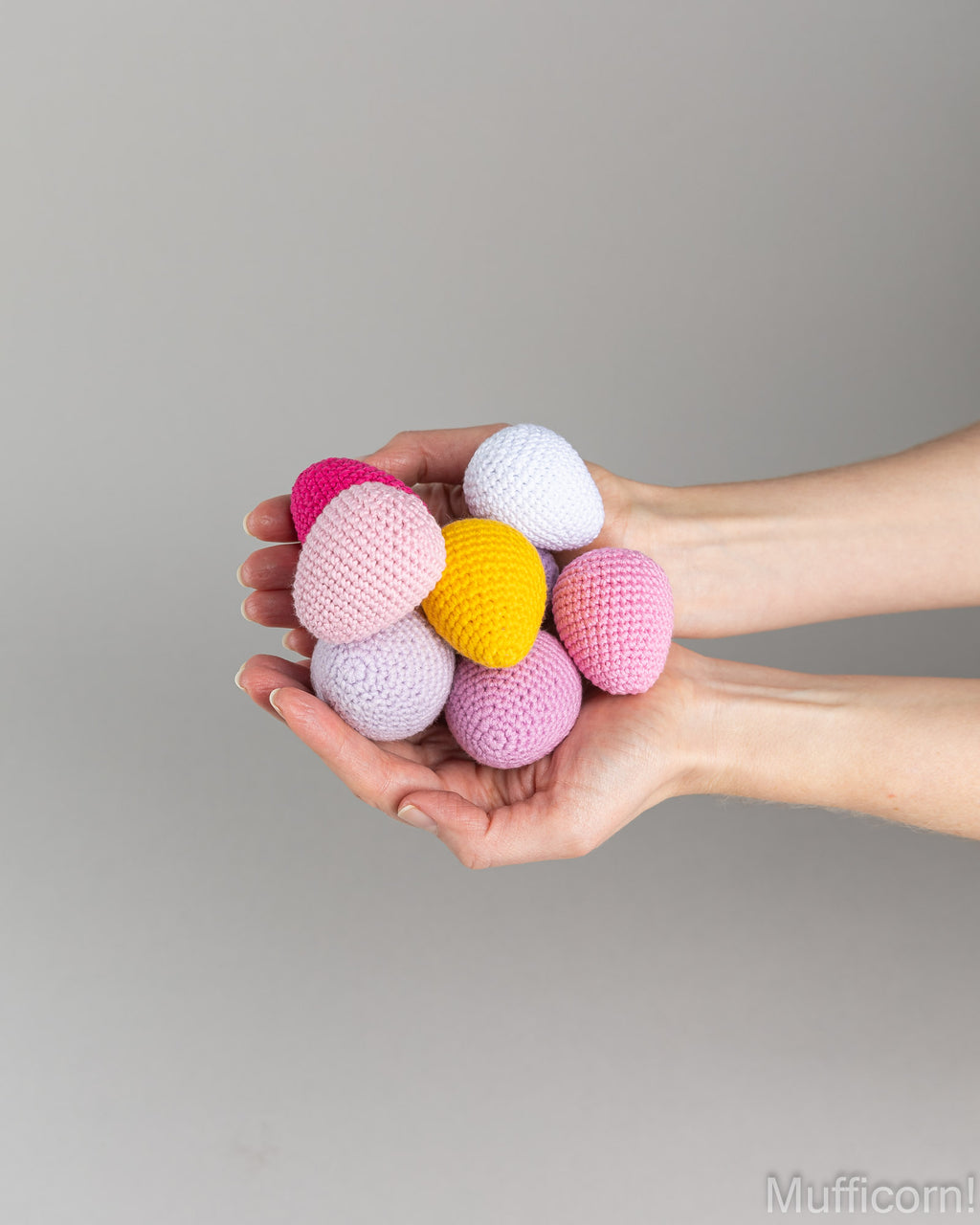 crochet eggs in different colors in person's hands