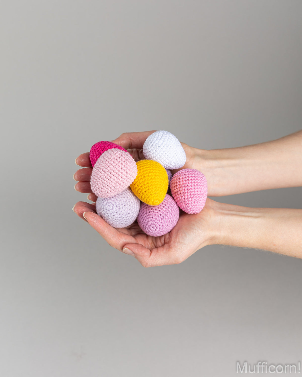 crochet eggs in different colors in person's hands