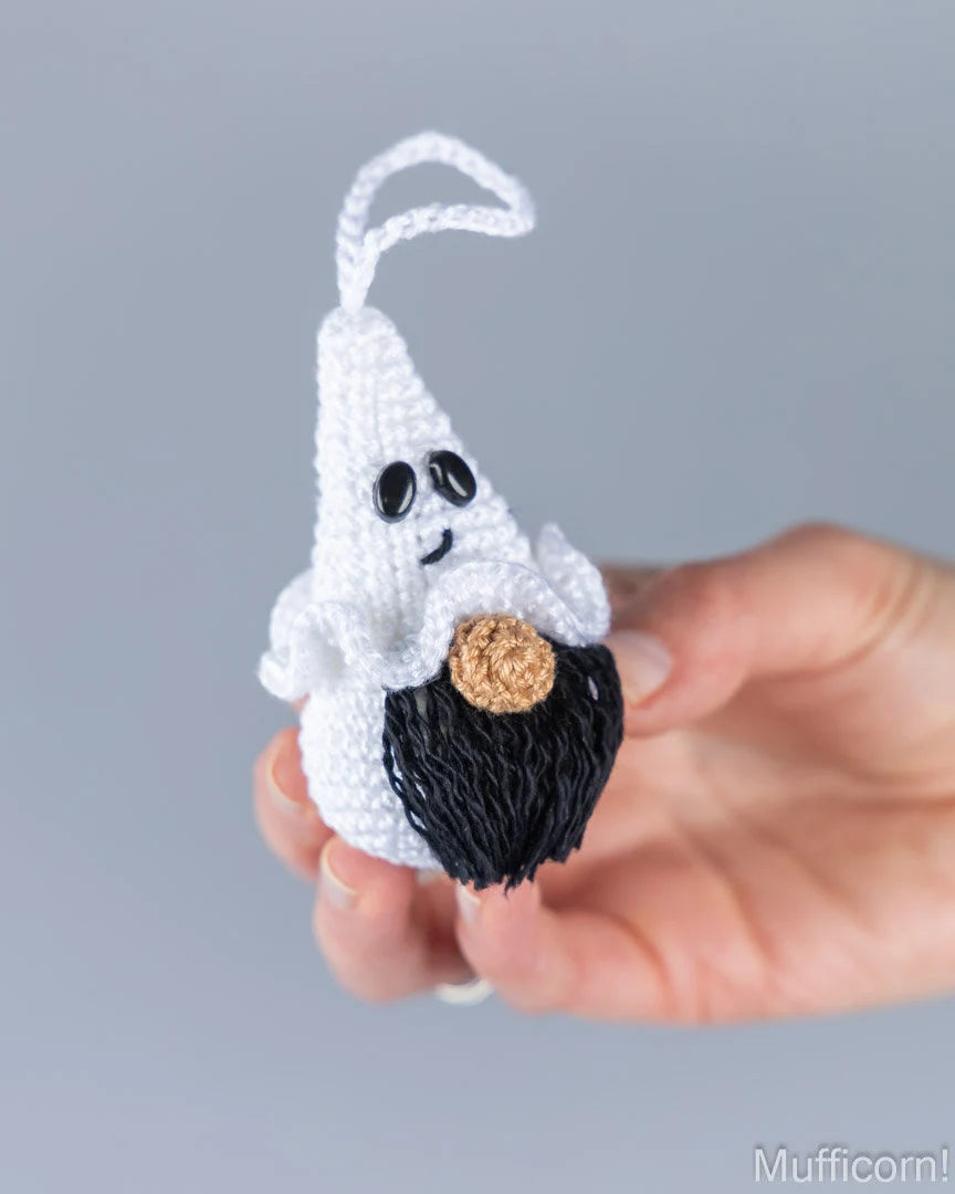 Crochet ghost gnome keychain with black beard held in hand