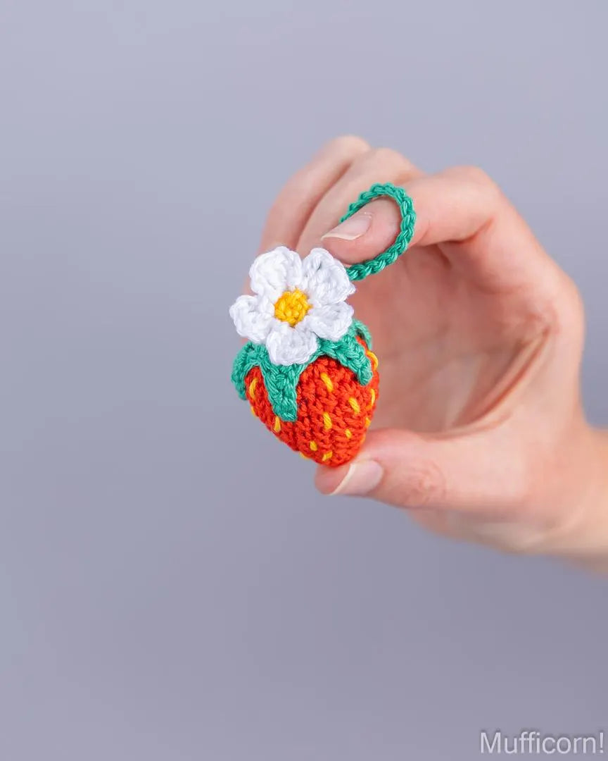 Single crochet strawberry keychain with flower held in hand