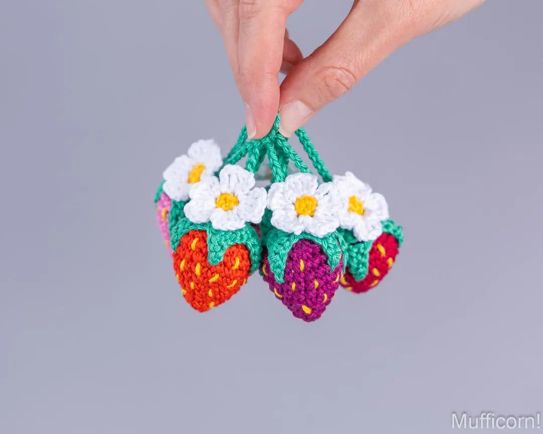 Colorful crochet strawberry keychains held in hand
