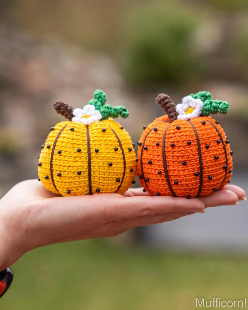Yellow and orange crochet pumpkins held in hand