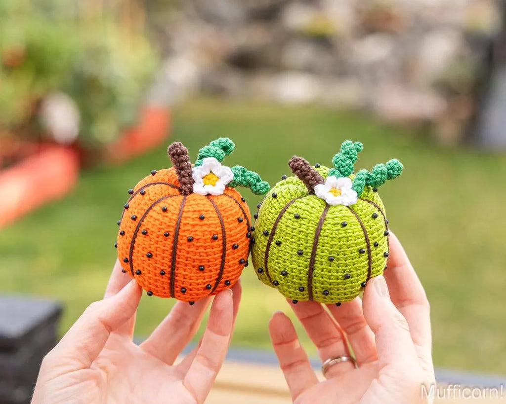 Orange and green crochet pumpkins held in hand