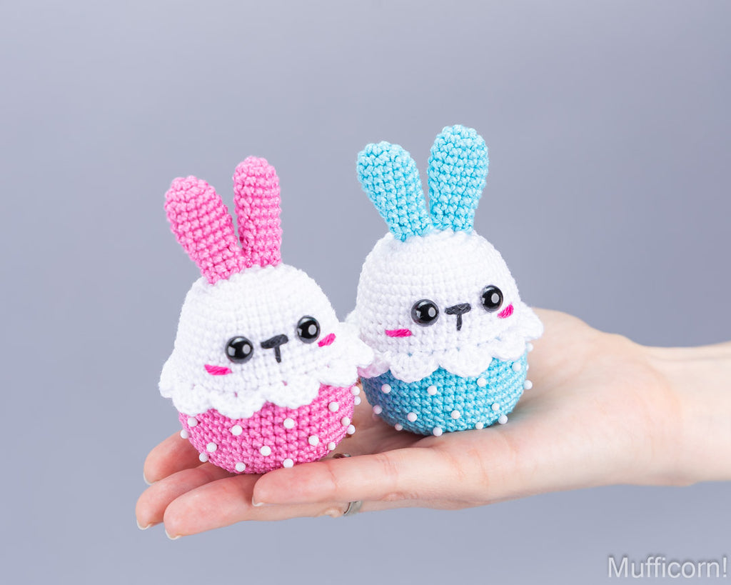 Pink and blue crochet Easter bunnies held in hand