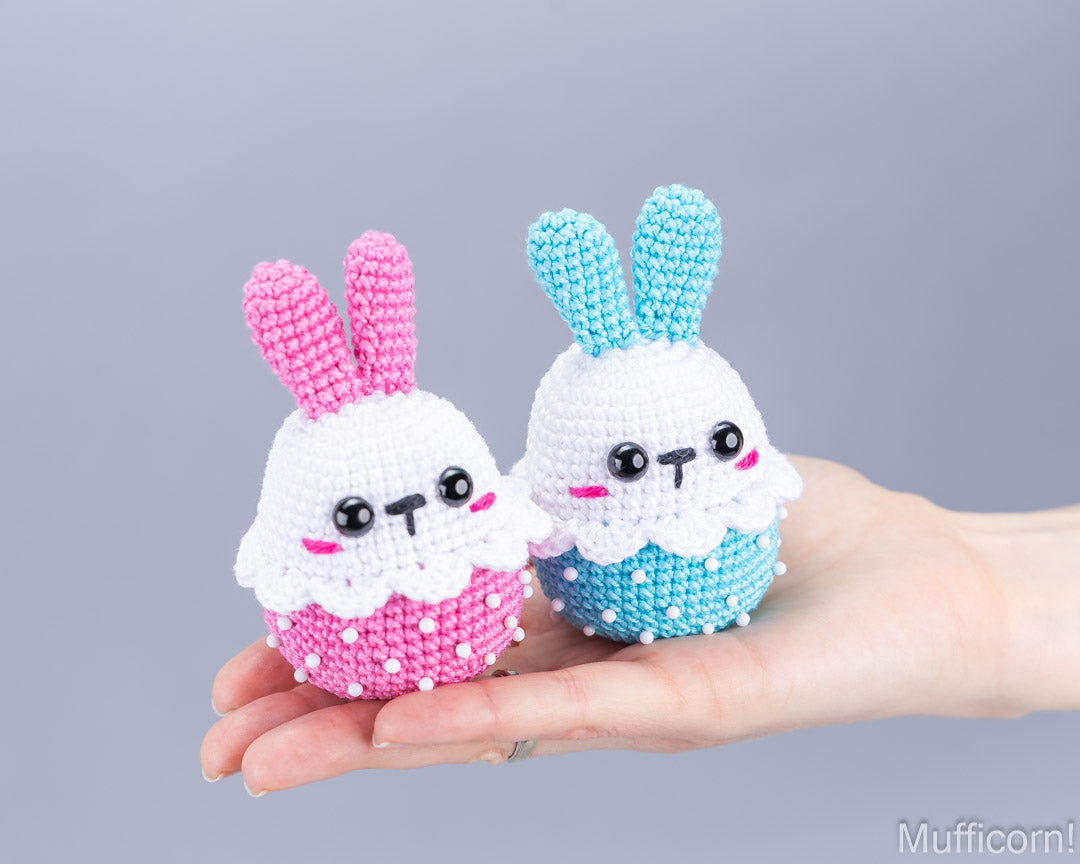 Pink and blue crochet Easter bunnies held in hand