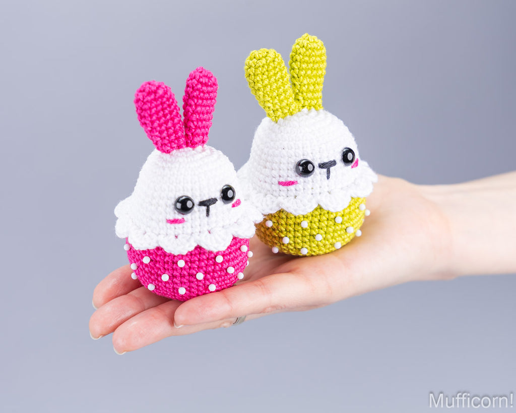 Pink and yellow crochet Easter bunnies held in hand