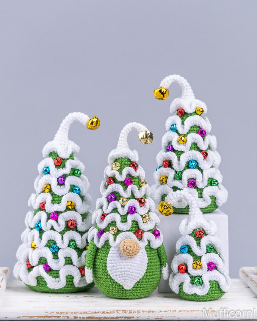 Four crocheted Christmas tree ornaments in green and white, decorated with colorful beads and small gold bells, arranged on a white surface against a light gray background.
